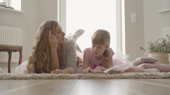 Happy Blond Caucasian Mother and Little Daughter Laying on the Floor on Fluffy Carpet at Home