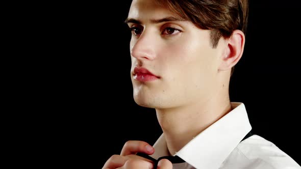 Androgynous man adjusting bow tie