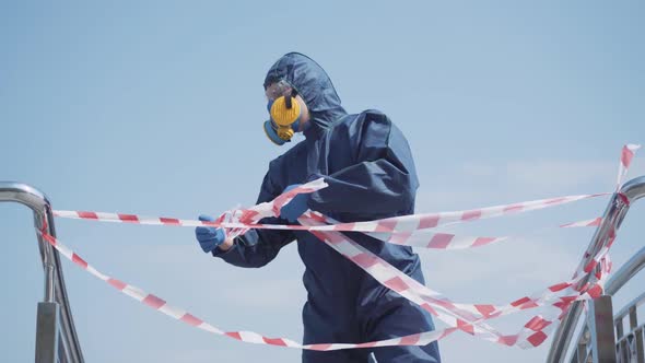 Man in Chemical Suit Tearing Off Caution Tape and Leaving. Portrait of Caucasian Young Guy in