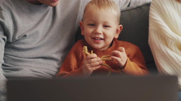 Happy little child watching something on laptop with his parents