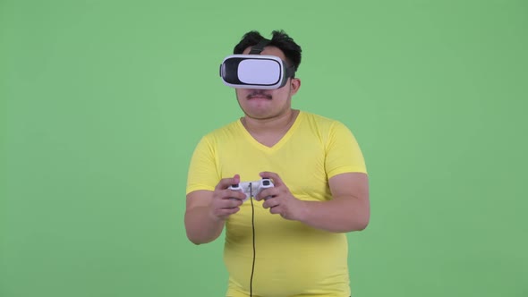 Happy Young Overweight Asian Man Playing Games While Using Virtual Reality Headset