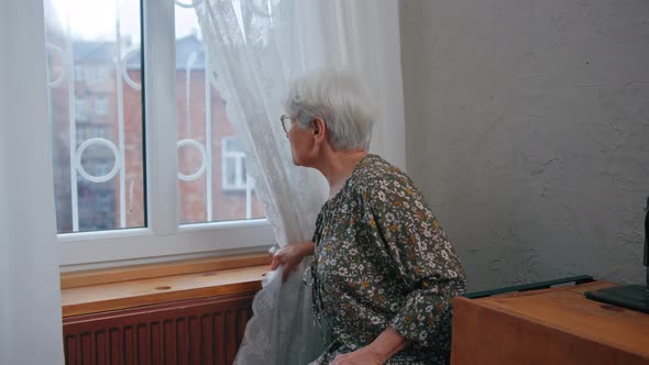 Caucasian Sad Lonely Pensive Elderly Woman with Short Grey Hair and Wrinkled Face Looking Through