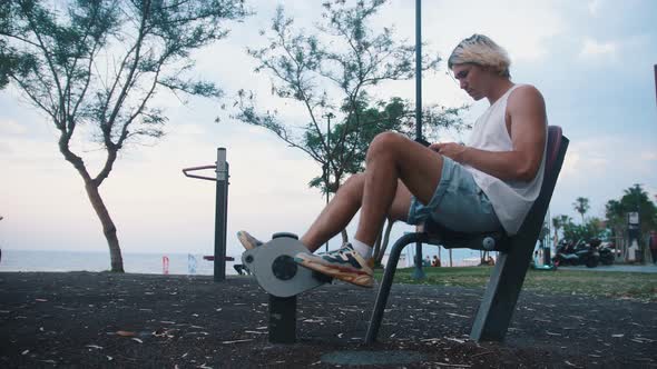 A Young Man on an Exercise Bike on a Street Sports Ground