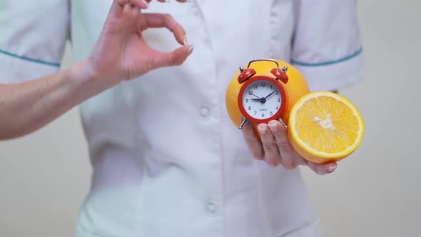 Nutritionist Doctor Healthy Lifestyle Concept - Holding Orange Fruit and Alarm Clock