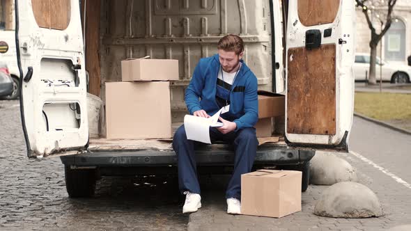 Delivery Driver Checking His List of Parcels