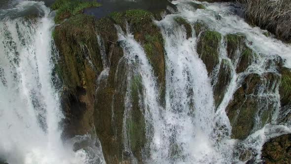 Flying view of waterfall flowing over edge into river