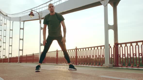 Young White Man in Black Sport Uniform Doing Warmup Before Run Pedestrian Bridge at Dawn