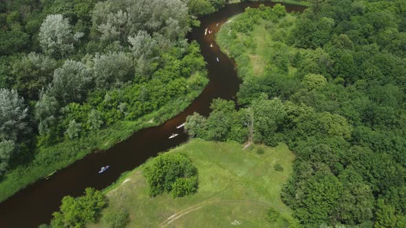 Aerial View of a Group of Kayaks Traveling on a Forest River on a Summer Day