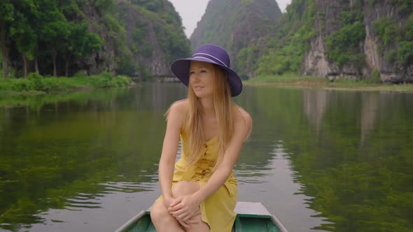 A Young Woman on a Boat Having a River Trip Among Rocks in Ninh Binh a Tourist Destination in