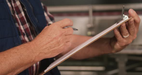 Male worker maintaining records on clipboard