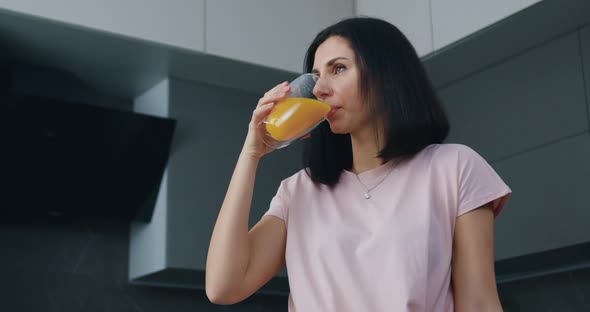 Woman in Pink t-shirt Drinking Fresh Orange Juice in Beautifully Decorated cuisine