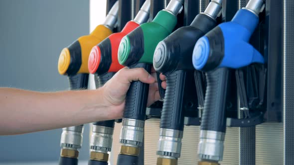 Male Hand Takes Out a Green-handled Gas Nozzle From the Pump