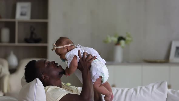 Loving Affectionate African Dad Playing and Kissing Infant Mixed Race Daughter