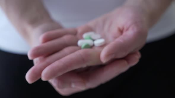 Woman Holding Pills in Hand Close Up