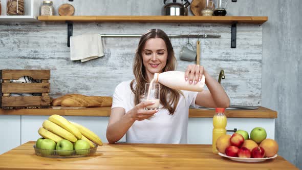 Portrait of Smiling Female Pouring Drink Yoghurt From Bottle Into Glass