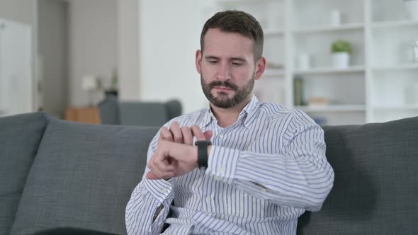 Attractive Young Man Using Smart Watch at Home 