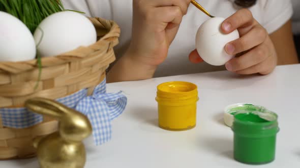 Children drawing on painted eggs at the table, at home. Preparing for the Easter holiday.