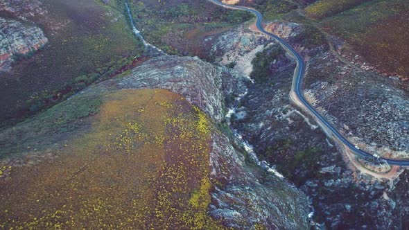 Tracking drone shot in Franschhoek mountain pass of cars on curvy road, South Africa