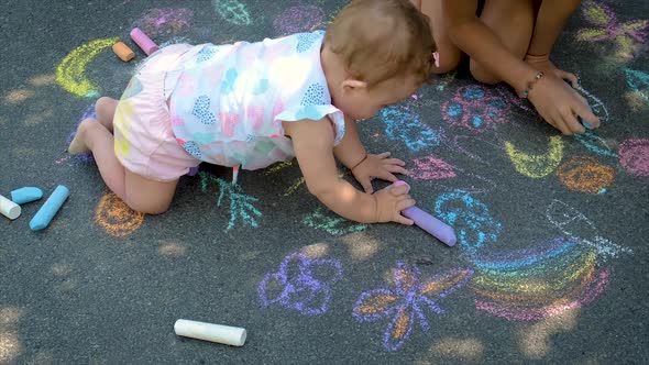 The Child Draws with Chalk on the Asphalt