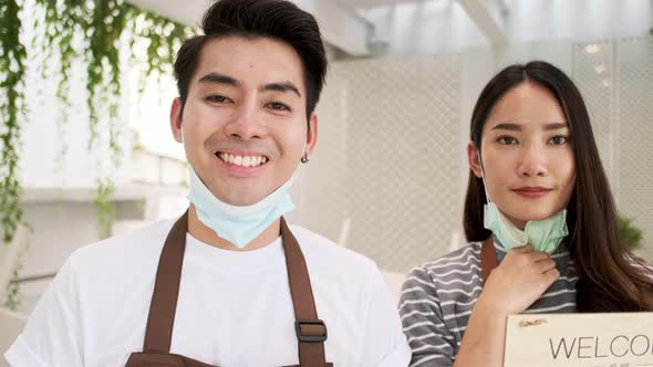 Business owner attractive young Asian  in apron hanging we're open sign