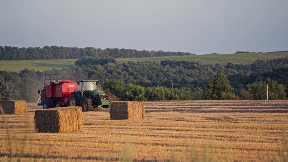 Haystacks on the field and tractor working on the natural green background