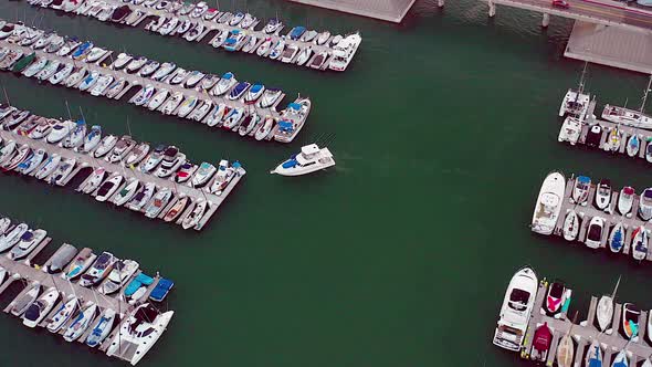 Drone footage of a boat pulling up to the dock, in a Harbor. Footage was captured at the Dana Point