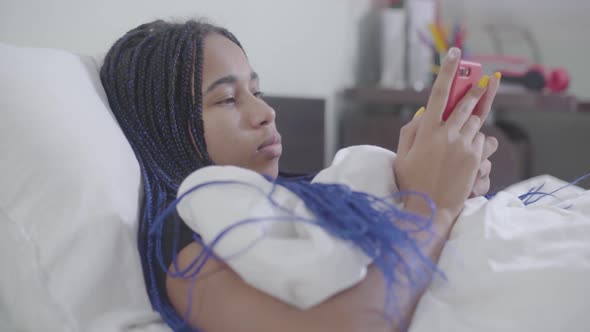 African American Girl with Dreadlocks Using Smartphone, Putting It Away and Looking Up Thoughtfully