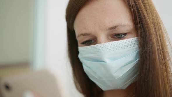 Woman in a Medical Mask Using a Smartphone