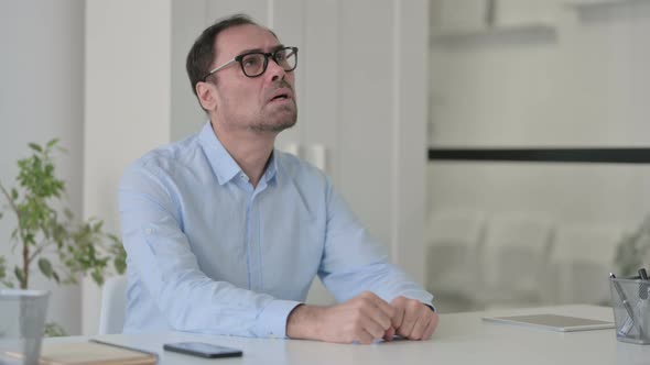 Upset Middle Aged Man Feeling Worried While Sitting in Office