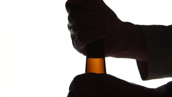 The Silhouette of Male hands opening brown beer bottle