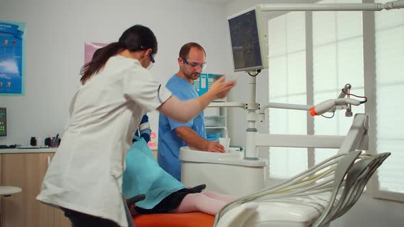 Stomatologist Pointing on Digital Screen Explaining Xray to Mother