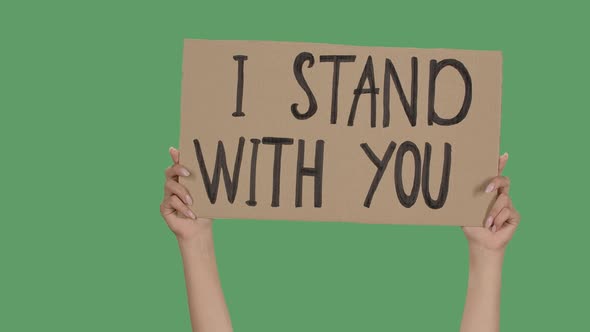 Female Hands Hold a Poster From a Cardboard Box with the Words I STAND WITH YOU. Protest Against