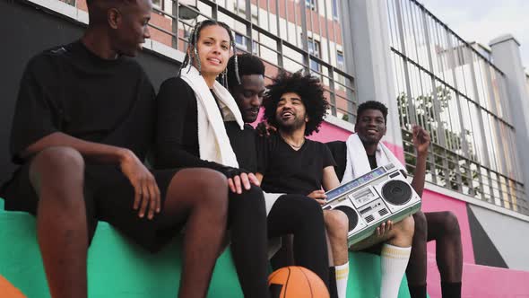 Young African American people having fun listening music with vintage boombox outdoor