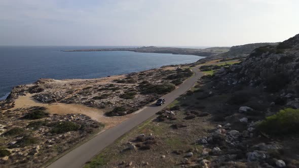 View of the sea surf near the rocks on the sea. Cars descend and drive along the road. Cyprus. alt