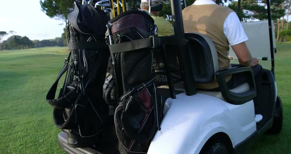 Two golfers driving in their golf buggy