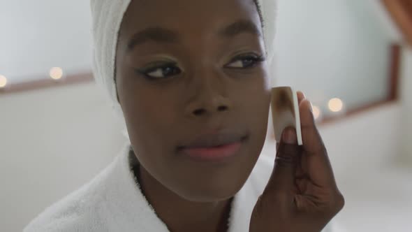 Portrait of african american attractive woman removing make up in bathroom