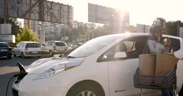 African Muslim Woman Charging Car and Use Phone