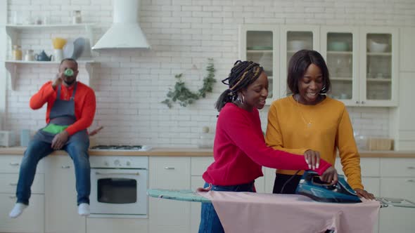 Black Teenage Daughters Helping Father Ironing Linen