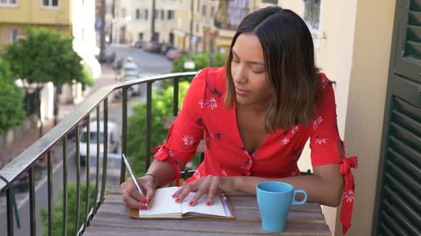 A woman writing in a journal diary traveling in a luxury resort town in Italy, Europe