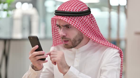Upset Arab Businessman Having Loss on Smartphone in Office