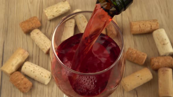 Wine is poured into a glass on the background of wine corks.	