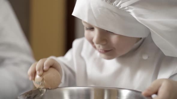 Closeup of Hands of a Young Chef Learning to Break Eggs