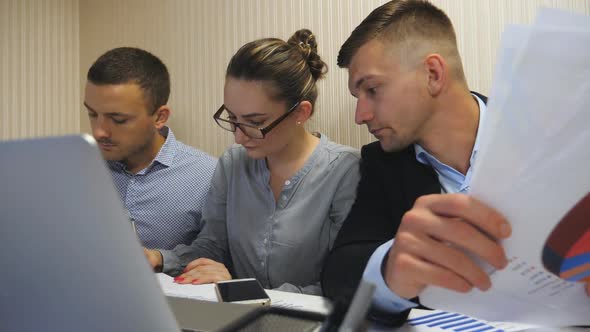 Group of Young Business People Sitting at Table in Modern Office and Working on New Project