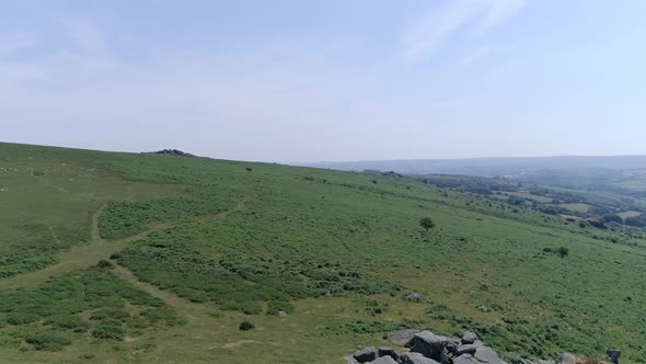 Wide shot aerial tracking forward over the wide expanse of Dartmoor, tors, grassy moorland and rocky