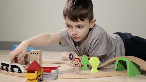 Cute boy plays with a wooden train, takes him across the bridge on flights. Wooden educational toys.