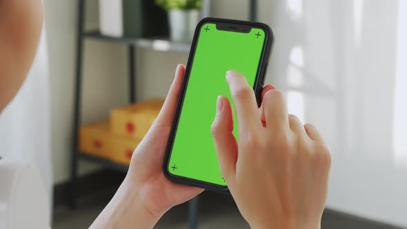 woman holding in hands a mock up smartphone with green screen for internet online