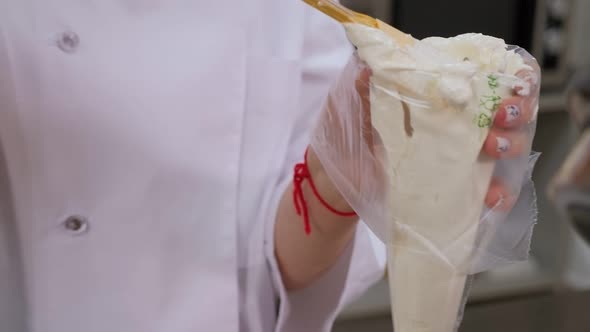 Closeup of a Chef Putting Cream in a Pastry Bag in a Professional Kitchen