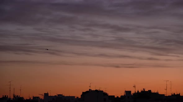 Helicopter against colorful sunset sky over city
