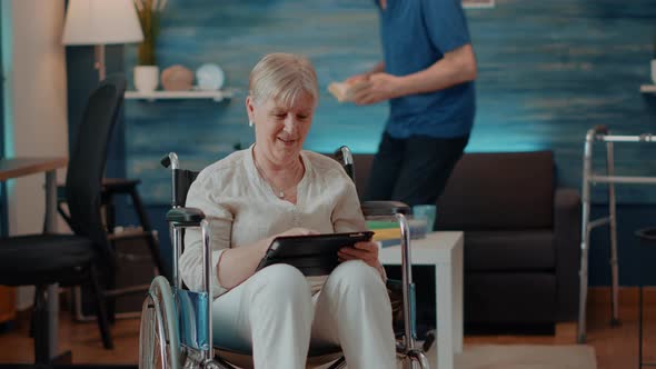 Aged Woman Using Digital Tablet While She Sits in Wheelchair