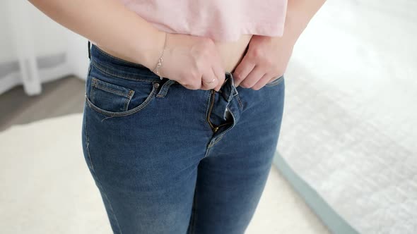 CLoseup of Young Woman Upsets After Fitting and Trying to Button Up Small Jeans